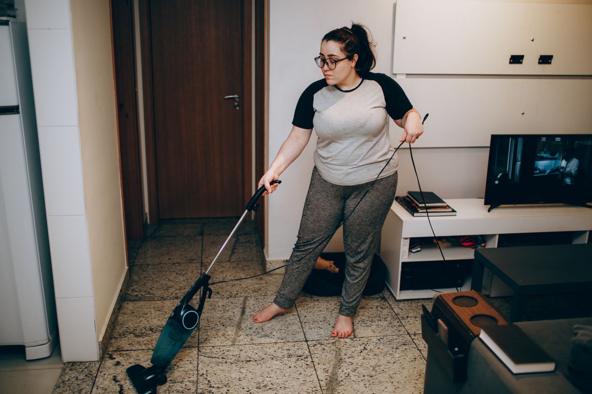 A person vacuuming the floor in a living room