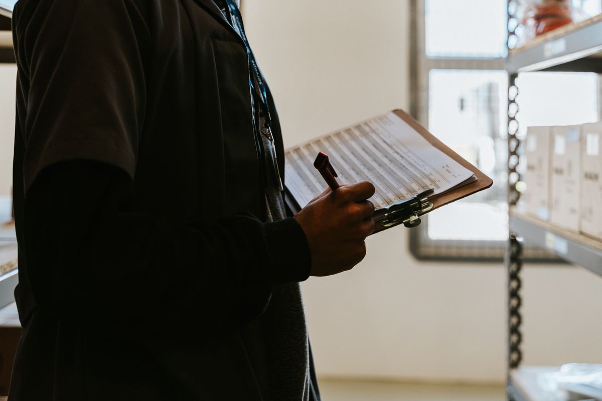 A warehouse worker checking an inventory list on a clipboard