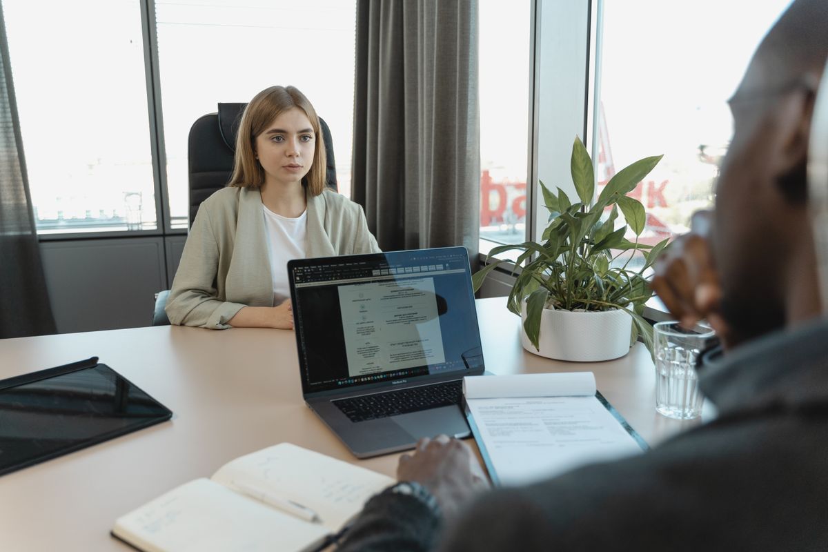 A candidate speaking with an interviewer across an office desk