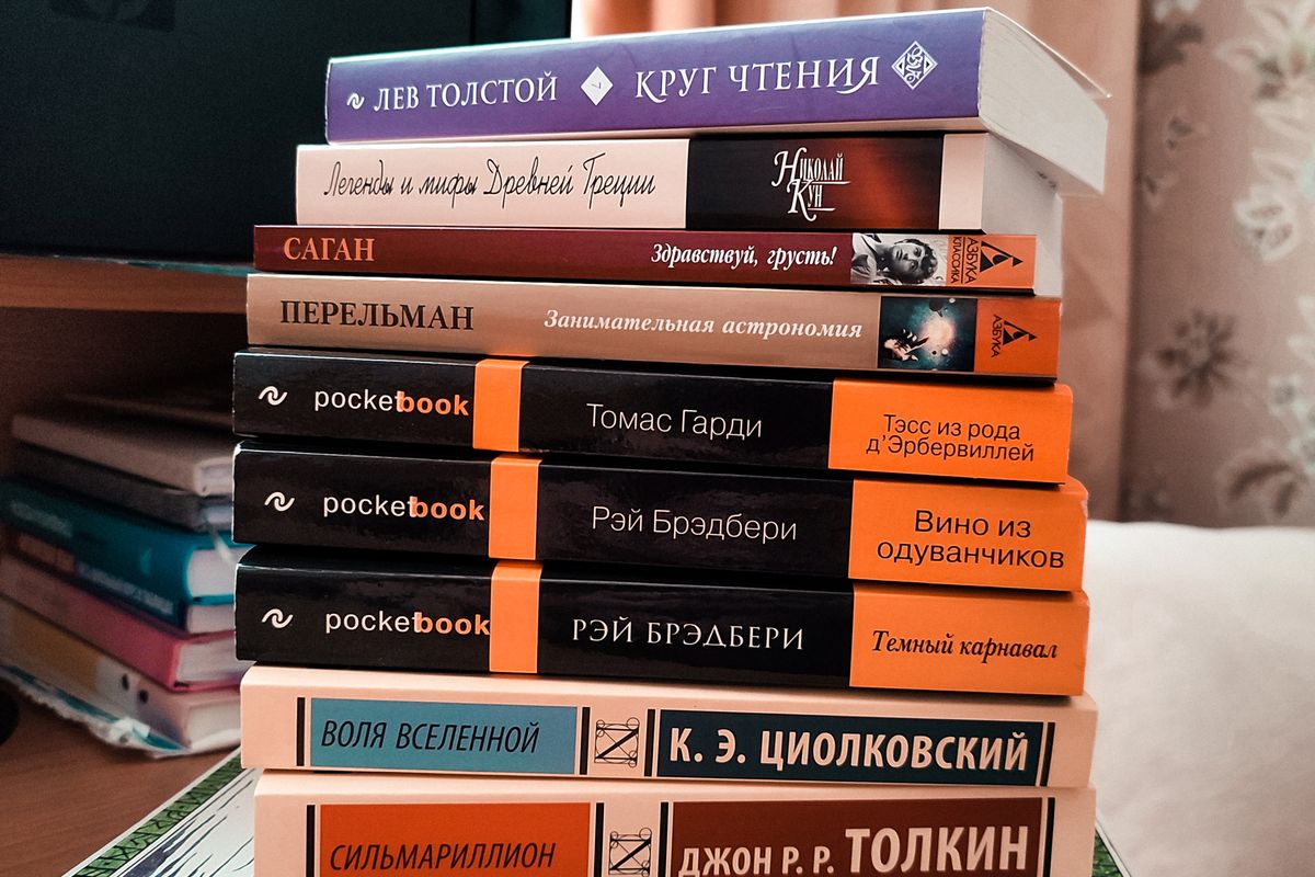 A stack of books in different languages on a wooden table