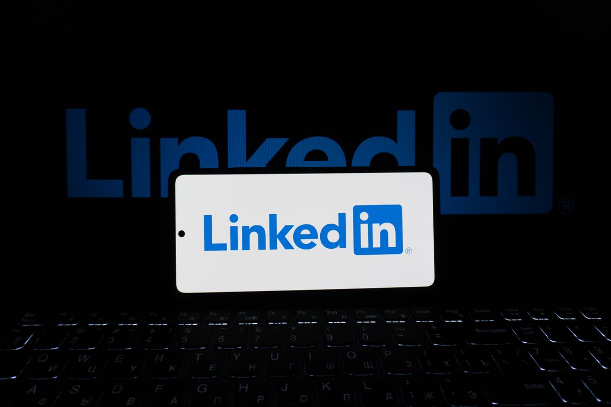 The LinkedIn logo displayed on a smartphone beside a laptop