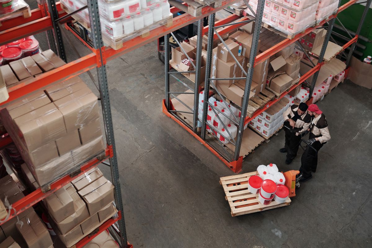 Warehouse employees managing stock between storage shelves