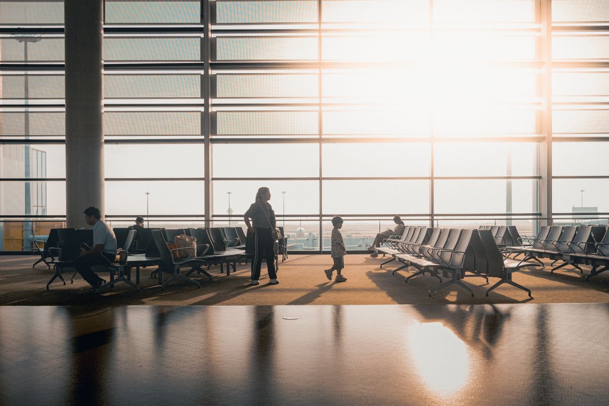 Travelers in a sunlit airport terminal preparing for an international journey