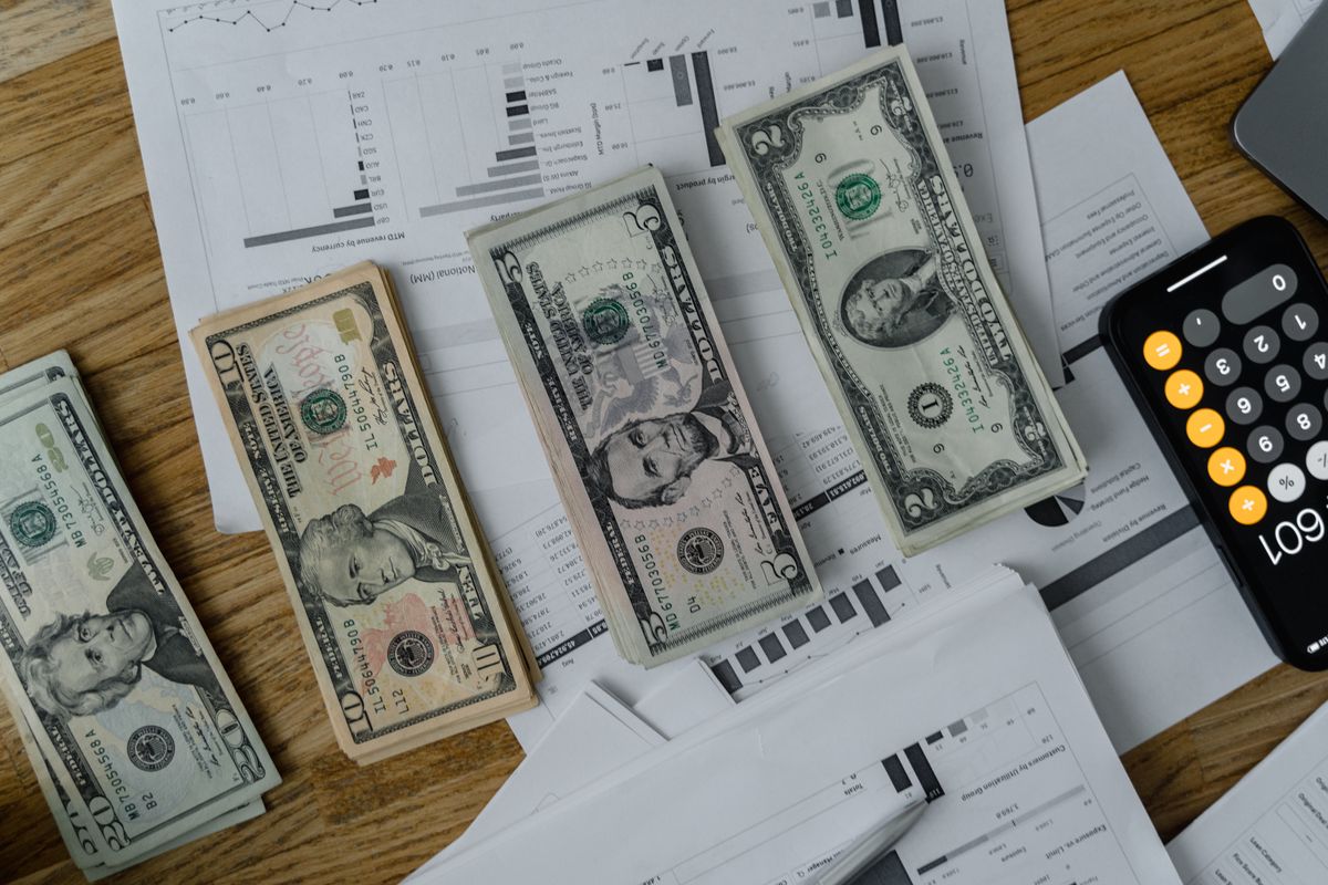 Cash, financial paperwork, and a calculator on a desk