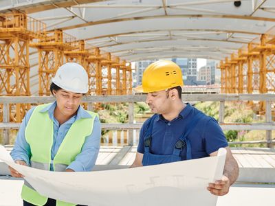 Engineers in safety equipment reviewing plans on site